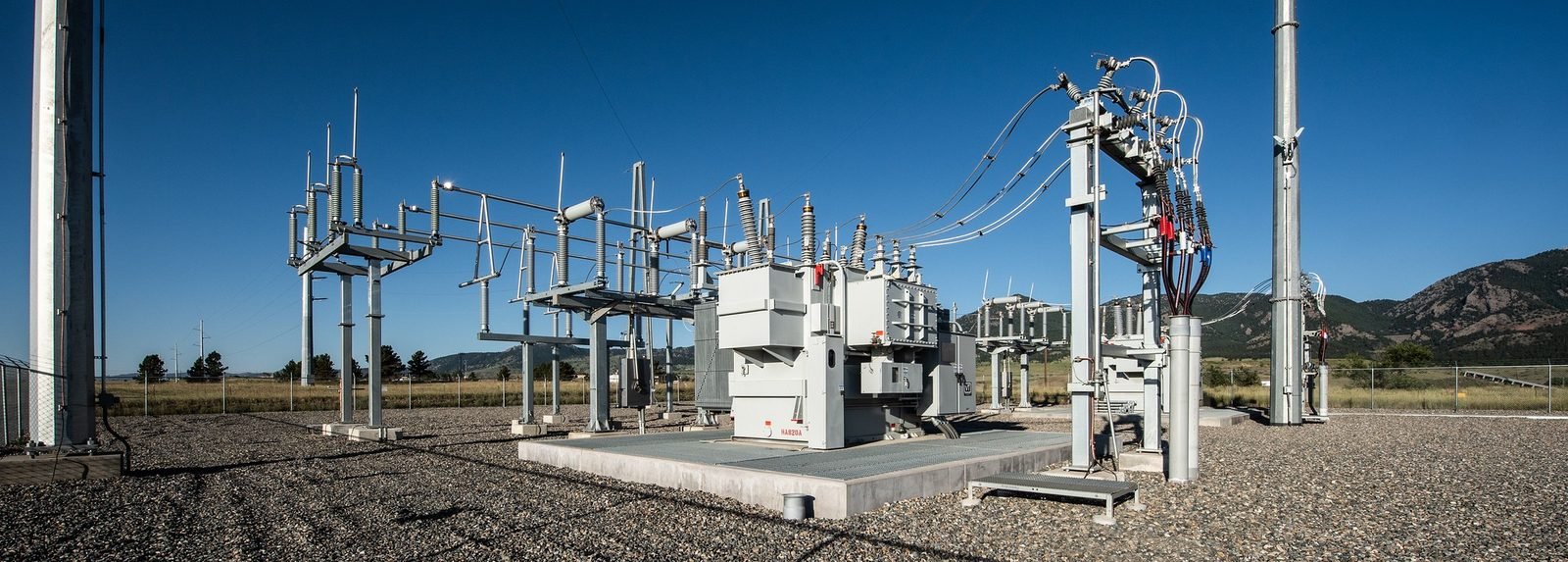 Subestación eléctrica de alta tensión con transformadores y torres de transmisión.