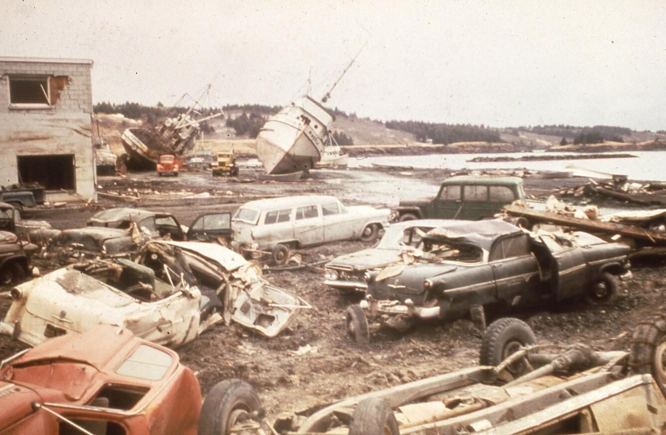 Coches, camiones y dos grandes barcos pesqueros arrastrados tierra adentro en el puerto de Kodiak, Alaska, por el tsunami de 1964.